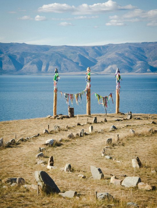 Colorful ribbons adorn ritual posts by a serene mountain lake.