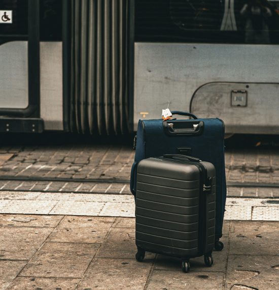 Two suitcases on street beside a tram in Florence, Italy, highlighting travel theme.