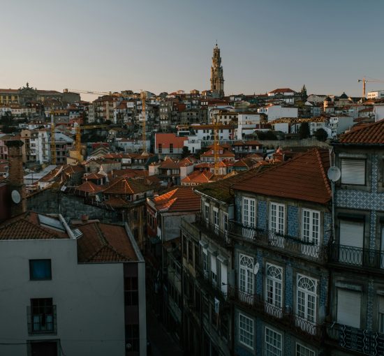 Dramatic aerial view of Porto's historic cityscape with red roofs and iconic architecture at dusk.