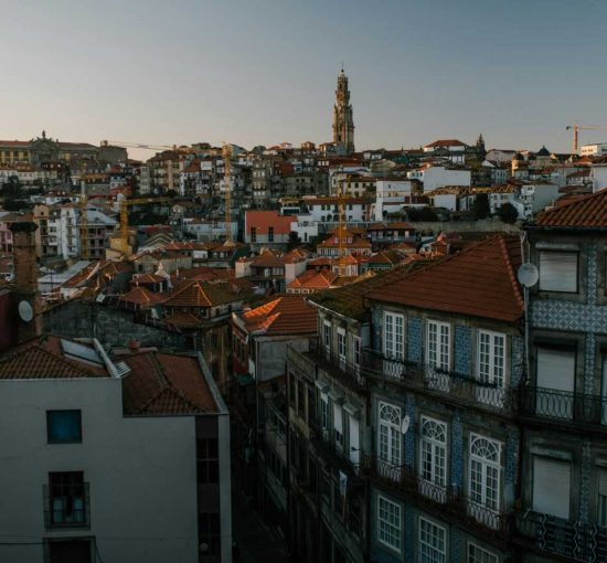 Dramatic aerial view of Porto's historic cityscape with red roofs and iconic architecture at dusk.
